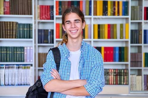 Preview: Single portrait of smiling confident male student teenager looking at camera in library
