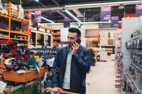 Preview: a buyer with a shopping cart is talking on the phone in a building materials store
