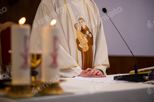 Preview: Hands of a catholic priest on altar with candles and microphone for reading a holy book