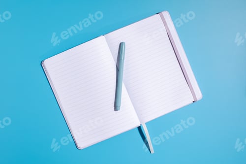 Preview: An open notebook with a pen on a blue background. A place for the text.