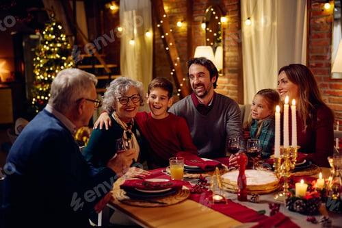 Preview: Joyful extended family talking at dining table on Christmas eve.