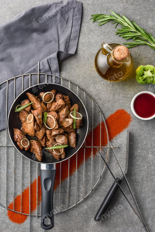 Preview: top view of fried meat in fried pan on metal grille with oil, broccoli and sauce