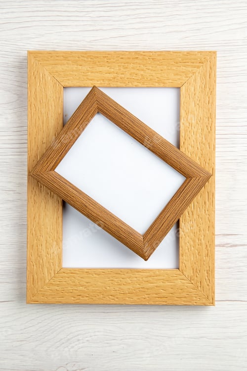 Preview: Top view of stacked medium and small empty picture frames on white wooden background