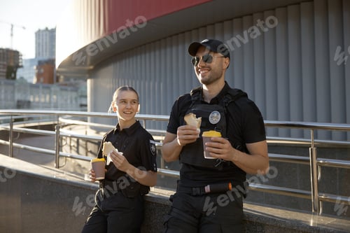 Preview: Male and female patrol police officers enjoying lunch break outdoor