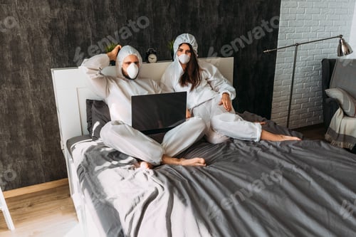 Preview: Relaxed Couple in Hazmat Suits Sharing a Laptop