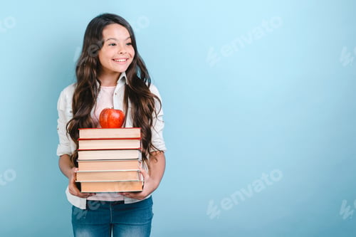 Preview: Portrait of smiling nerd young girl holding stack of books with apple on it. Back to school.