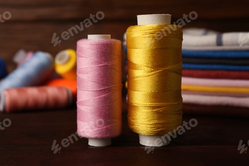 Preview: Different sewing threads on wooden table, closeup. Tailoring accessories