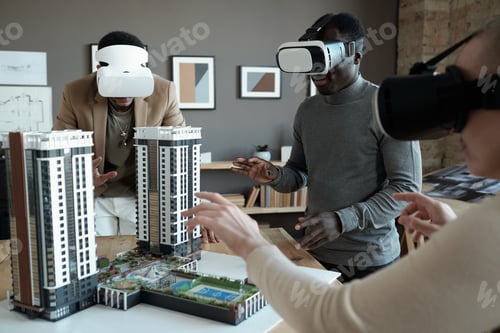 Preview: Group of architects in vr headsets standing around table with house layout