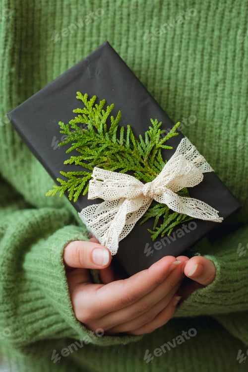 Preview: Cozy Christmas present in woman's hand, close up