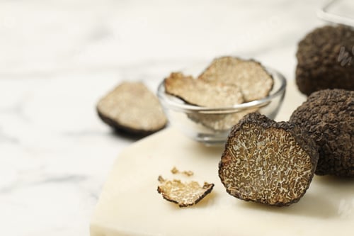 Preview: Whole and cut black truffles with board on table, closeup. Space for text