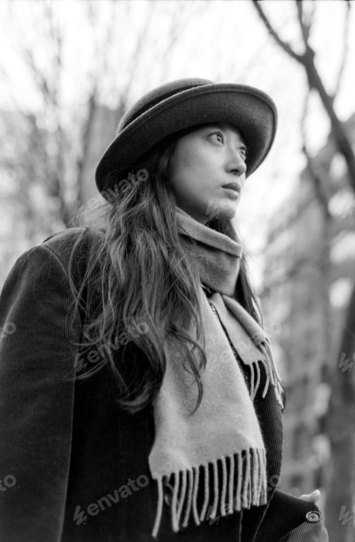 Preview: Young woman wearing hat and scarf posing in monochrome analog photo