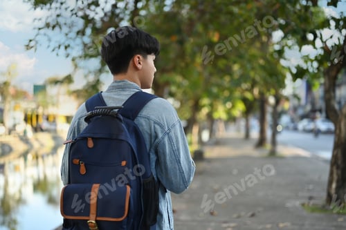 Preview: Rear view of male traveller with backpack walking in old city in Chiang Mai Northern Thailand.