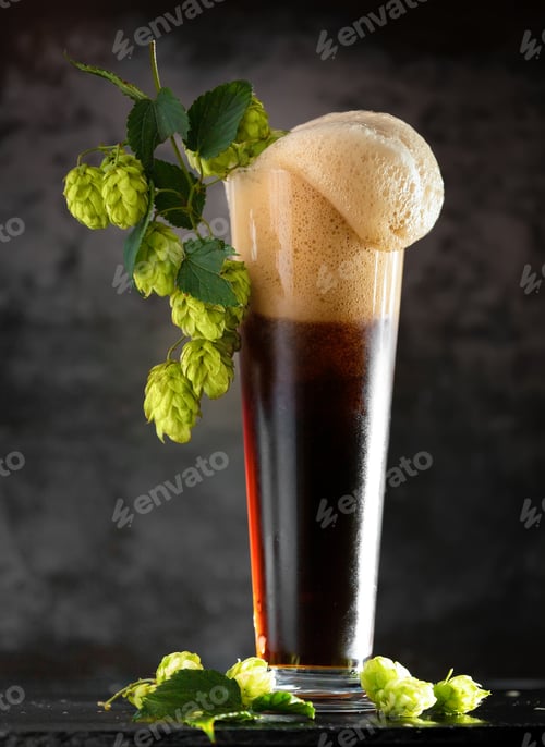 Preview: Glass of dark beer with hops around on a dark background