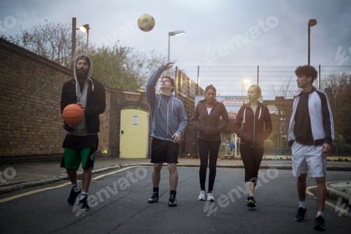 Preview: Group of adults walking in road, holding basketball and football