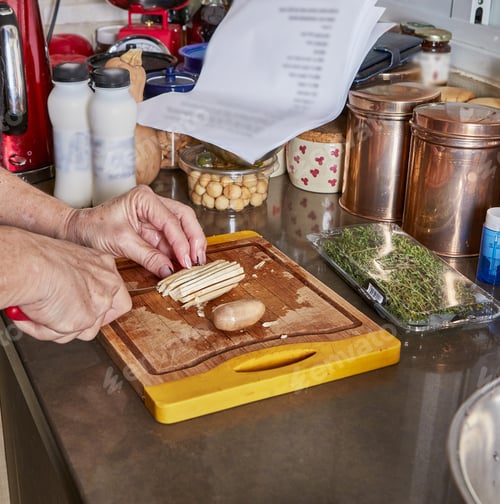 Preview: Woman prepares recipe at home in the kitchen. Cuts mushrooms on wooden cutting board