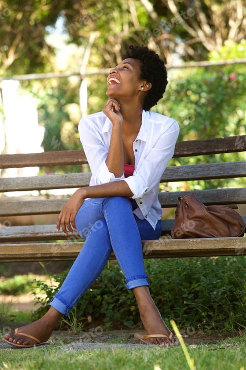 Preview: African woman laughing on a park bench