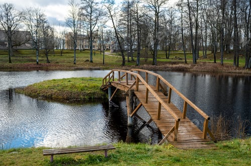 Preview: A small wooden bridge from the shore to a small island in the lake in the manor park