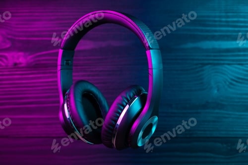 Preview: Black headphone on dark wooden background. Stylish wireless headset in neon light.