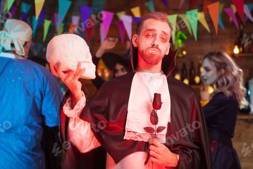 Preview: Attractive man dressed up like vampire with a human skull at halloween party