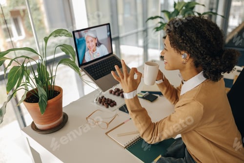 Preview: Smiling female manager have video conference with client and showing sign Ok while sitting in office