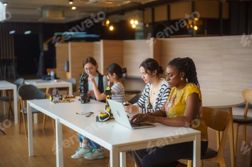 Preview: Diverse group of women and girls collaborating on a robotics project in a modern classroom setting