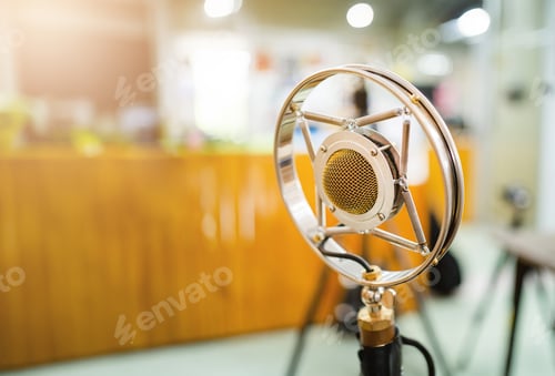 Preview: A microphone is sitting on a stand in front of a wooden desk.