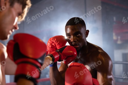 Preview: Sportsman muay thai boxer training fighting in gloves in boxing cage at the gym.