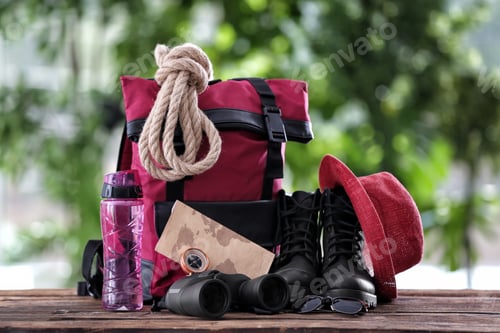 Preview: Composition with backpack and camping equipment on table against blurred background