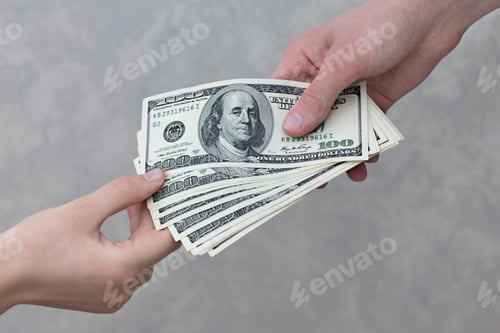 Preview: A man's hand stretches a stack of one hundred dollar bills into a woman's hand close-up