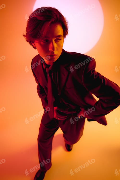 Preview: Stylish young man posing confidently against a vibrant backdrop at sunset