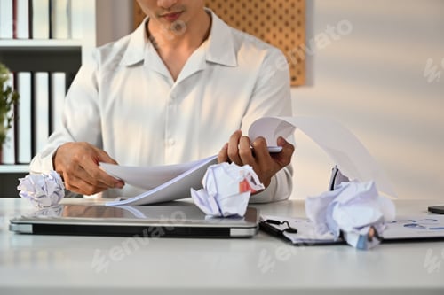 Preview: Cropped sot of male entrepreneur working with account documents at white office desk.