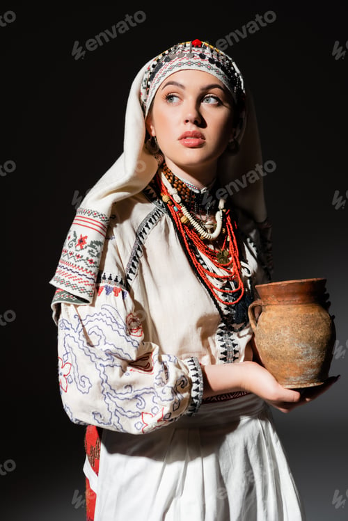 Preview: portrait of pretty ukrainian woman in traditional clothing with ornament holding clay pot on black