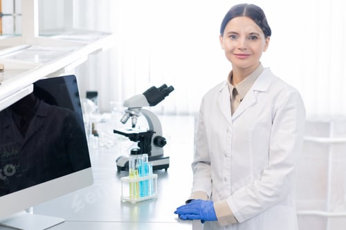 Preview: Young successful female scientist or pharmacist in gloves and whitecoat