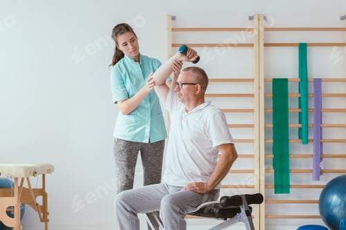 Preview: Physiotherapist assisting a senior patient performing weight exercises