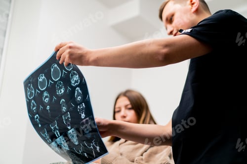 Preview: the doctor shows a picture of a brain tomography to a sick patient in the hospital
