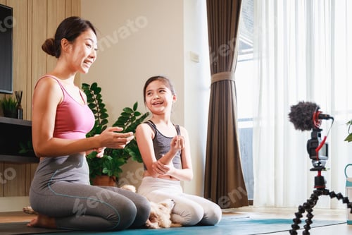 Preview: Asian woman yoga teacher and Girl filming yoga online class on video.