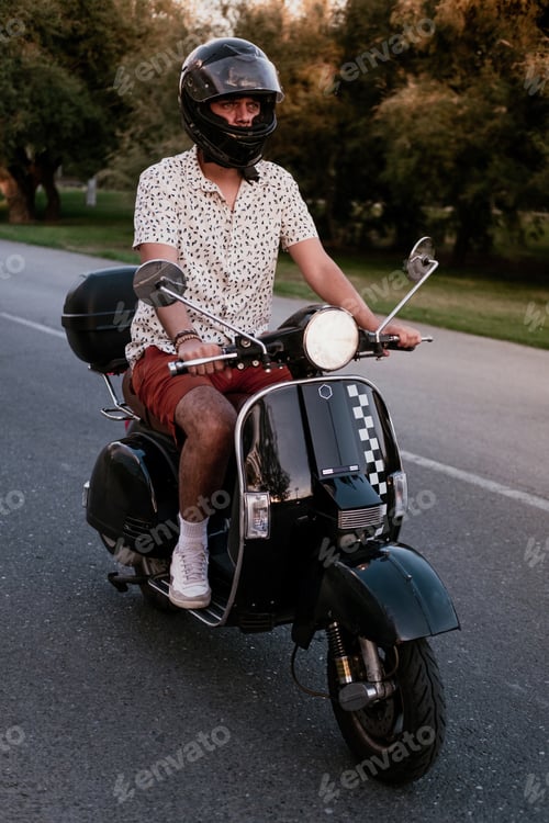 Preview: Young handsome male with hipster outfit rides a black vintage motorbike in motion