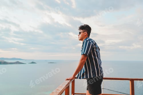 Preview: Asian man enjoying sea view from balcony