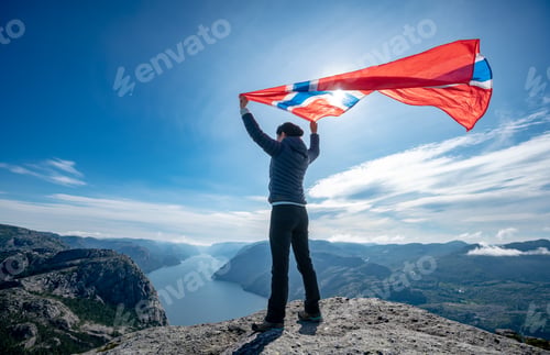 Preview: Woman with a waving flag of Norway on the background of nature