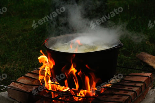 Preview: Cooking fish soup in the iron bowler over a campfire. Fish soup boils in cauldron at the stake. Soup
