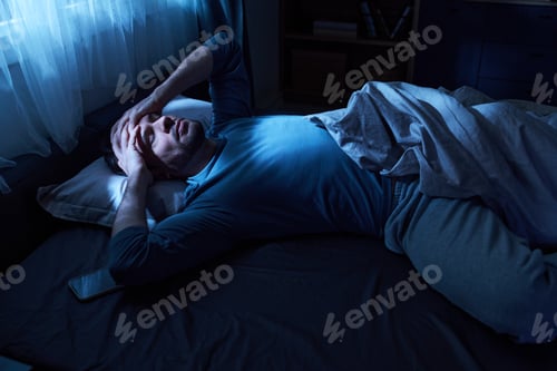 Preview: Adult Man Lying in Bed Suffering from Insomnia at Night