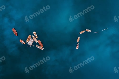Preview: Aerial drone view of wooden boats on water surface with blue sky reflection in lake.