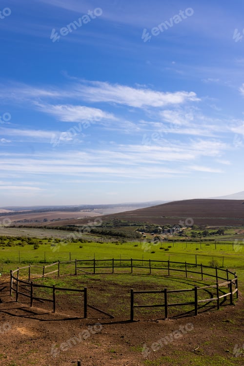 Preview: Vertical image of landscape of countryside and agricultural fields and round fence on sunny day