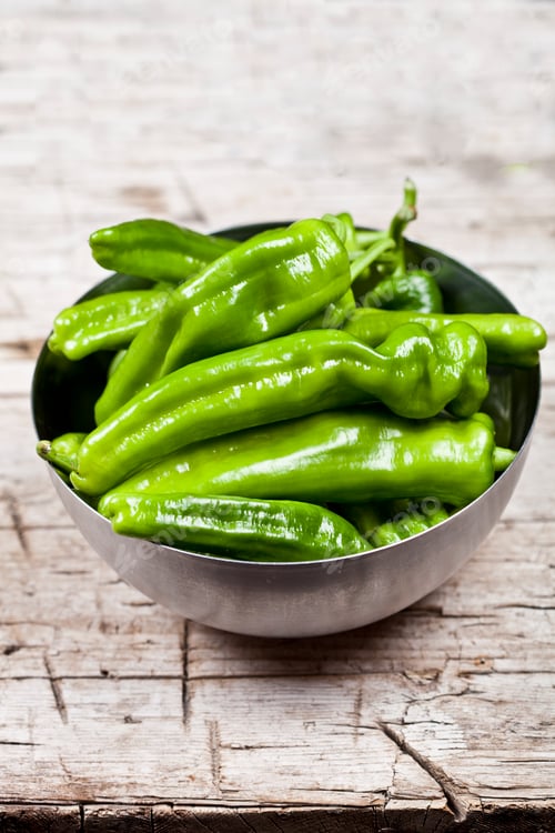 Preview: Fresh green raw peppers in metal bowl on rustic wooden table background.
