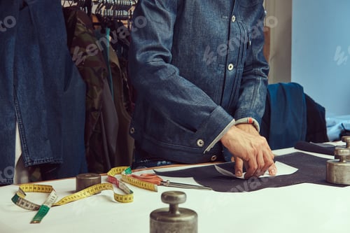 Preview: Cropped image of a tailor working with cloth samples at sewing workshop.