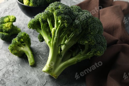 Preview: Broccoli, board and towel on grey background, close up. Healthy food