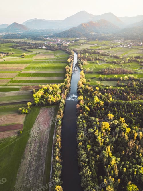 Preview: Vertical photo of a river running trough the country side with suburban communities scattered all