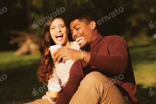Preview: Young couple enjoying a park on a sunny day and drinking coffee