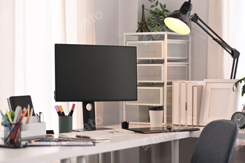 Preview: A blank computer screen, stationery and lamp on white table in modern home office interior.