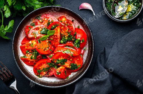Preview: Simple summer juicy tomato salad with parsley, dill, garlic and olive oil dressing, black table